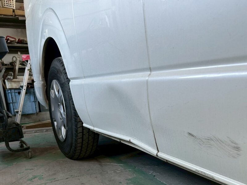 車両側面のパネルが広範囲に歪み、下部に凹みが見られる損傷状態